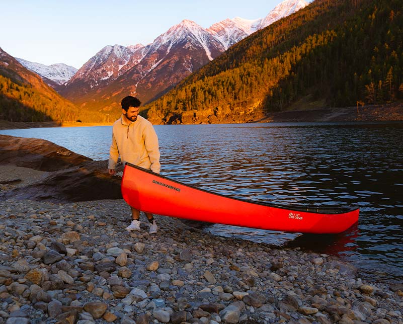 Man pulling an Old Town Discovery 158 canoe from the water